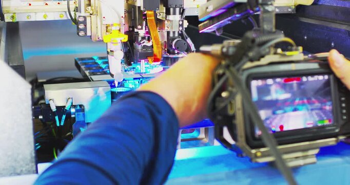 A videographer films the process of manufacturing a printed circuit board.