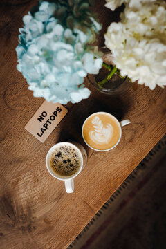 Cozy cafe table with coffee, flowers, and no laptop sign