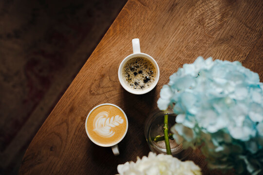 Cozy cafe table with coffee cups and hydrangea flower