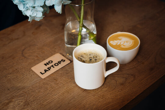 Cozy cafe table with coffee cups and no laptop sign