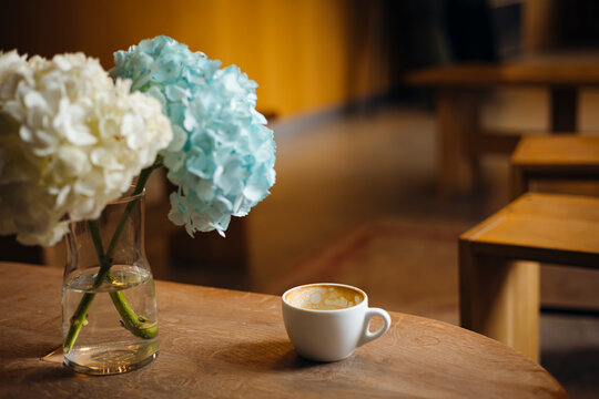 Cozy cafe table with coffee cup and hydrangea flower