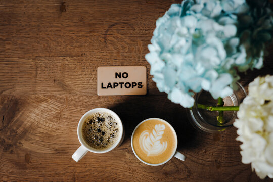 Cozy cafe table with coffee and a no laptops sign