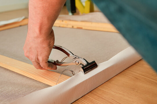 Stretching canvas on wooden stretcher with tension clamp