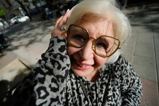 Smiling senior woman on street wearing headphones outdoors
