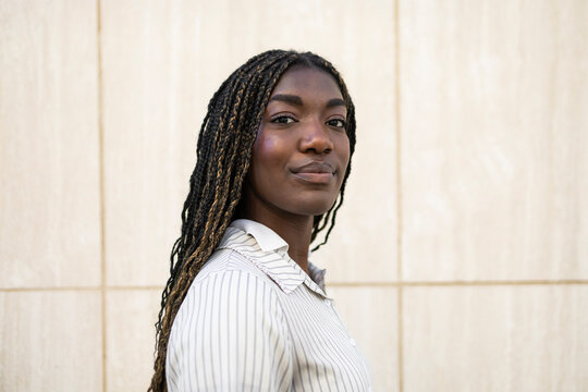 Confident woman with braided hairstyle smiling outdoors