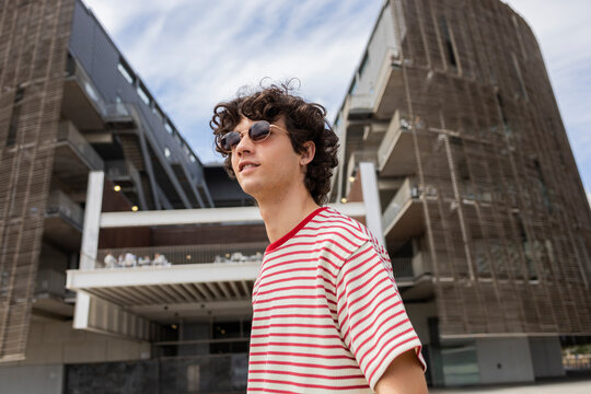 Curly haired man in sunglasses enjoying urban lifestyle scene