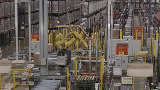 M&aacute;quina industrial automatizada moviendo cajas en f&aacute;brica, sistema de transporte y manipulaci&oacute;n de materiales en planta de producci&oacute;n