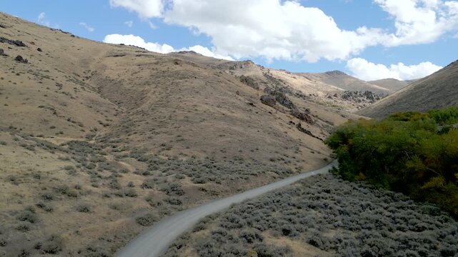 Aerial views of a rocky hillside just outside of Winnemucca Nevada the drone follows a road leading to the top of the mountain.