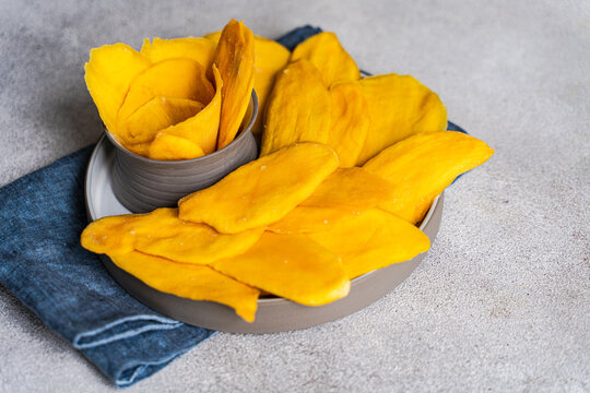 Delicious dried mango slices on ceramic plate