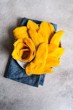 Plate of vibrant dried mango slices on table