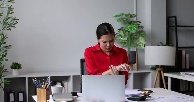 Woman feeling wrist pain after long hours of office work on laptop. Suffering from carpal tunnel syndrome. Repetitive strain injury. Or muscle inflammation. Needing rehabilitation and physical therapy