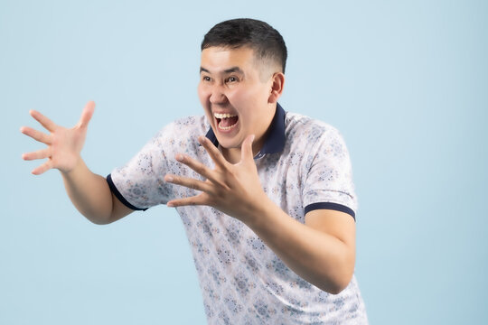 Angry young man reaching hands forward screaming in extreme rage or fear