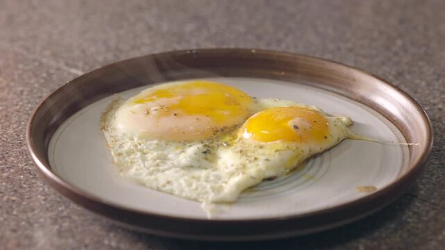hot and steaming fried eggs on a plate for breakfast