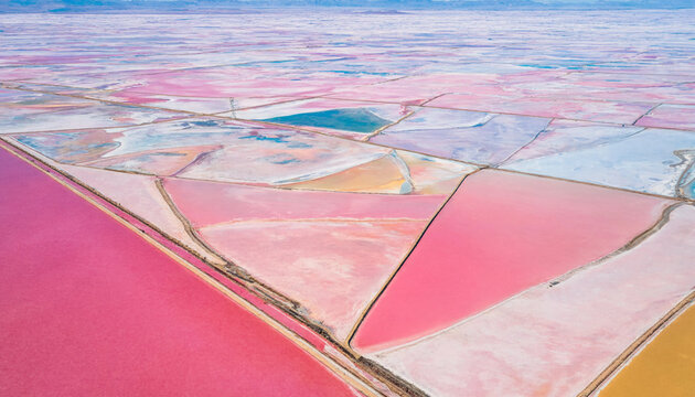 Aerial perspective of vast pink salt pans with geometric evaporation basins landscape evaporation geometric industry harvesting environment crystals extraction production material