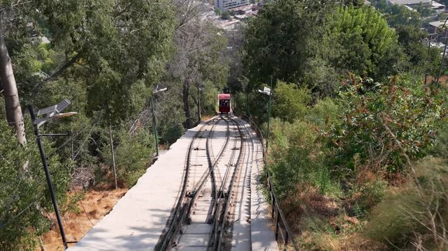 Red funicular railway ascending the san cristobal hill with santiago city in the background