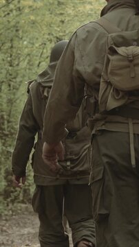 Group of Soldiers Marching In Forest. Historical Re-enactment. Re-enactors Dressed As American Soldiers Of USA Infantry Of World War II Marching Walking Along Forest Road In Autumn Day