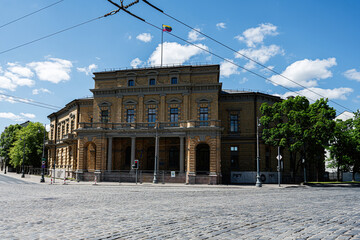 Naklejka premium Historic brick Wroblewski Library of the Lithuanian Academy of Sciences building with columns and Lithuanian flag in Vilnius, Lithuania overlooking a quiet cobblestone square on a sunny summer day