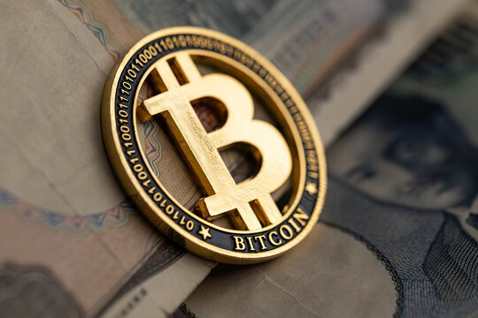 Gold Bitcoin coin on US dollar and Japanese yen banknotes