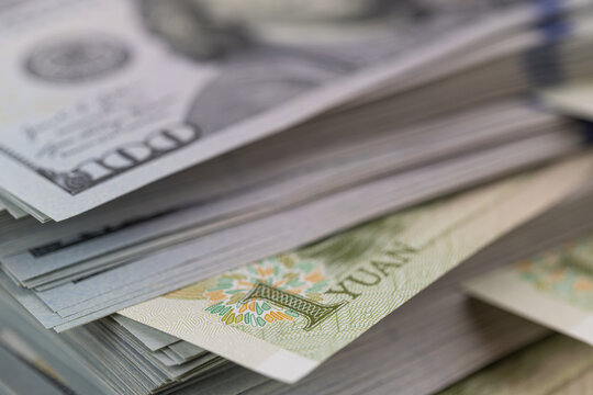 US dollar banknotes stack with Chinese yuan bills close up