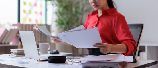 Professional woman managing business documents, working and reviewing papers on an office desk, organizing reports and financial paperwork for efficient workflow © David