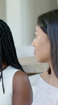 Vertical video: Panning revealing two women talking and smiling at patio with white sleeveless top