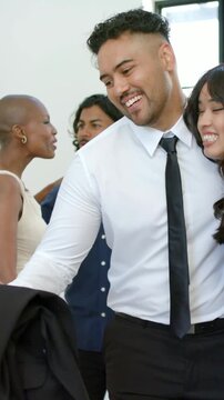 Vertical video: Man in white shirt reaching for jacket, greeting arriving woman in black at entry