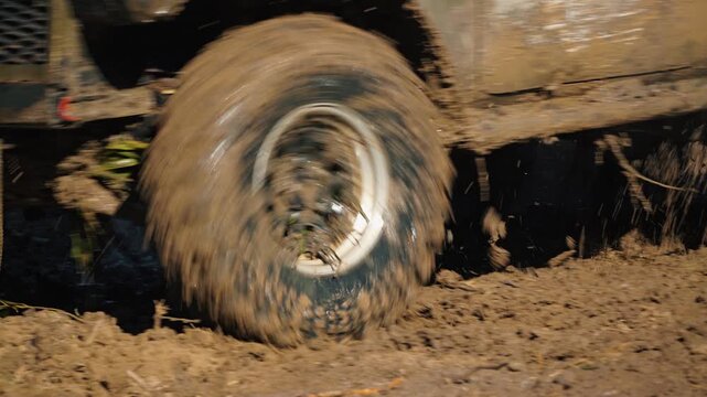 Close up of four wheel drive vehicle racing through thick mud. Spinning tire splashes dirt in extreme motorsport competition. Rugged, powerful, and adventurous concept with motion blur