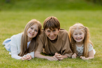 Fototapeta premium three children hugging on the lawn in the summer