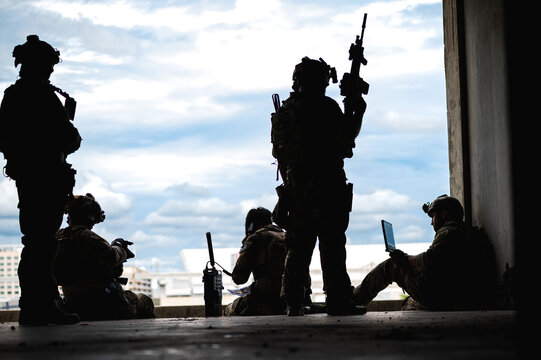 Silhouette special armed military squad team in full gear patrolling an abandoned building during hostage crisis