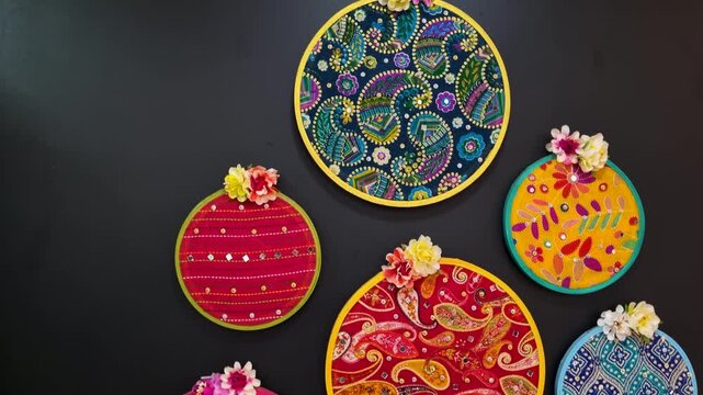 Colorful embroidery hoops with paisley patterns hanging on a black wall