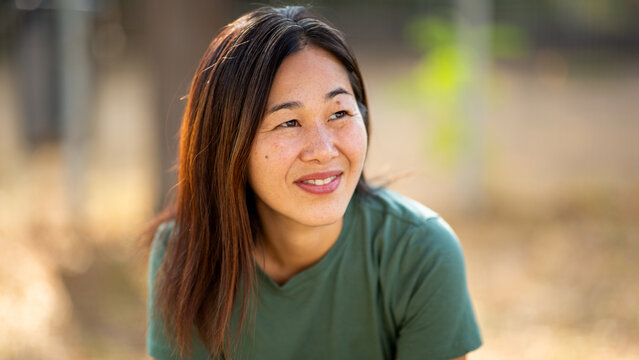 Asian woman portrait with thoughtful expression in natural outdoor setting
