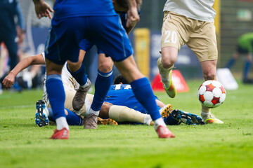 Naklejka premium Intense football challenge with players battling for the ball after a sliding tackle during a competitive soccer match