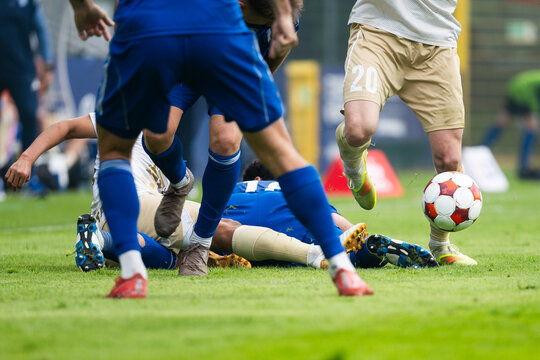 Intense football challenge with players battling for the ball after a sliding tackle during a competitive soccer match