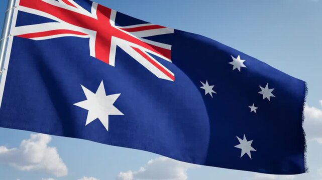 Australian flag with union jack, commonwealth star and southern cross constellation fluttering in wind against bright blue sky with white clouds. australian national pride and commonwealth identity