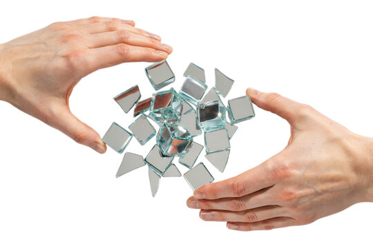 Hands holding shattered mirror pieces floating in air