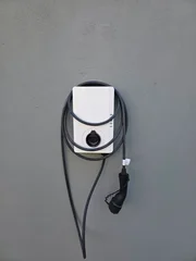 modern electric vehicle wallbox charging station installed on vintage house wall with extended charging cable © Simon Dux Media