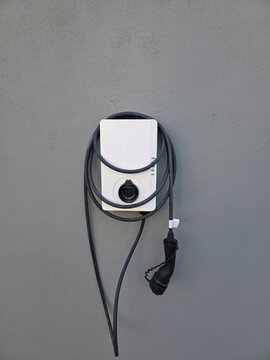modern electric vehicle wallbox charging station installed on vintage house wall with extended charging cable