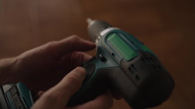 Professional worker inserting battery into cordless electric drill and selecting torque setting with hands, getting power tool ready for home improvement or construction jobs. Shooting in slow motion.