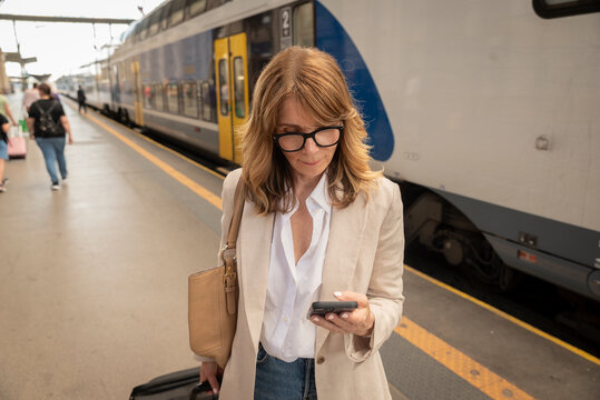 Mature businesswoman talking on smartphone while traveling by train at railway station