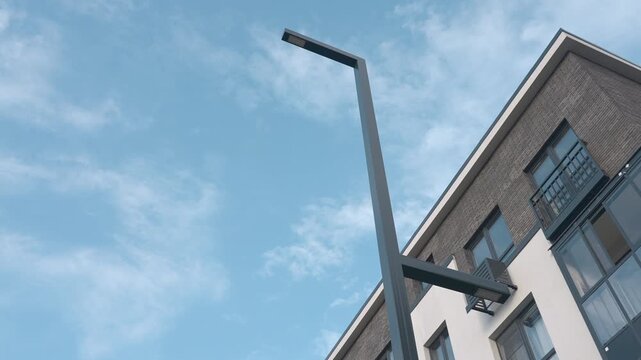 Modern apartment building beside streetlight under clear blue sky