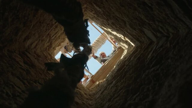 Biblical scene from a low angle view showing a rope descending into a dark ancient pit