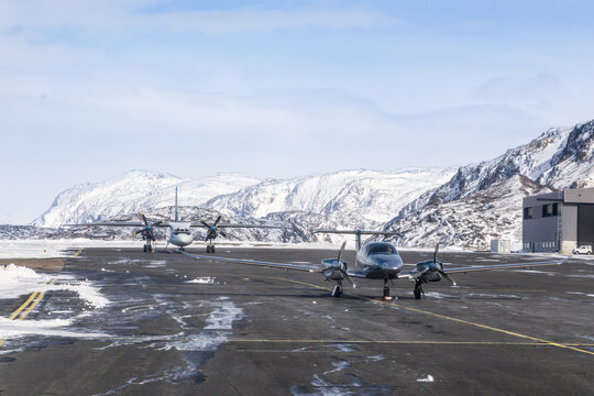 Small propeller planes on the tarmac at Narsarsuaq Airport with snow-covered mountains and winter aviation scenery, Narsarsuaq, Kujalleq, Greenland