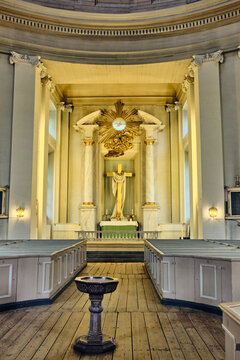 Karlskrona, Sweden - 14 September 2025: View of the interior of the Church of the Holy Trinity featuring the altar with a golden cross, wooden pews, and a baptismal font.