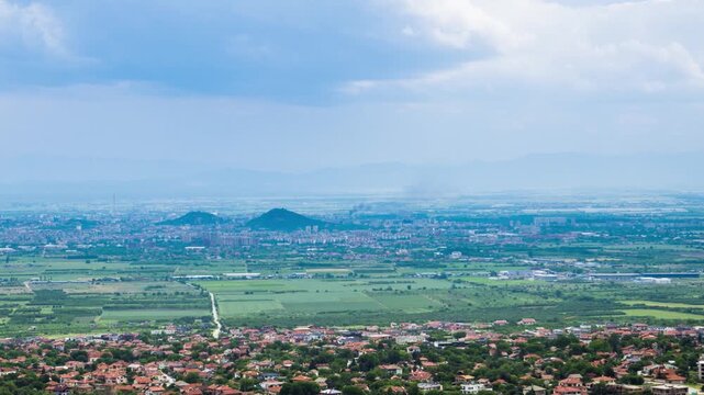 Town Plovdiv with houses and fields against backdrop of Rhodope Mountains and hills covered with forests and cloudy sky