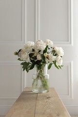 Fototapeta premium Bouquet of beautiful peony flowers on wooden bench indoors