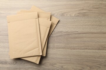 Naklejka premium Stack of kraft envelopes on wooden table, top view. Space for text