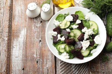 Tasty salad with boiled beet, cucumbers, feta cheese and dill on wooden table, flat lay. Space for text © New Africa