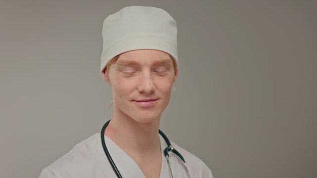 Caucasian senior surgeon determined stare, confident clinical posture with stethoscope, authoritative presence in neutral studio,