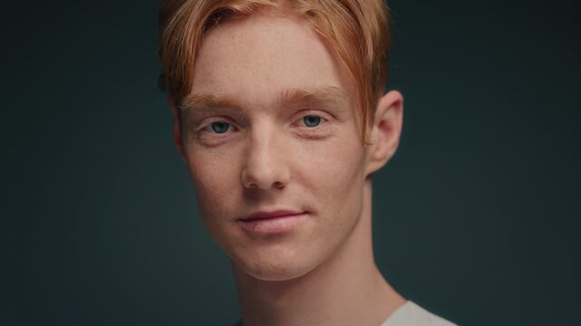 Closeup portrait white redhead actor, subtle expression. Studio headshot with teal background and soft cinematic lighting