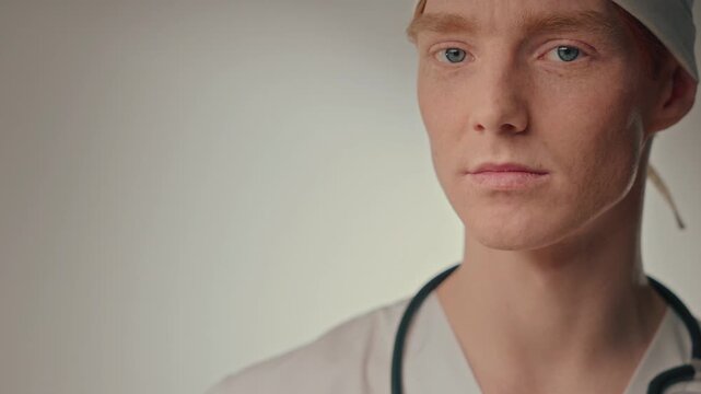Caucasian clinician inspecting syringe with focused gaze, gloved hand and white cap, sterile technique emphasized in neutral